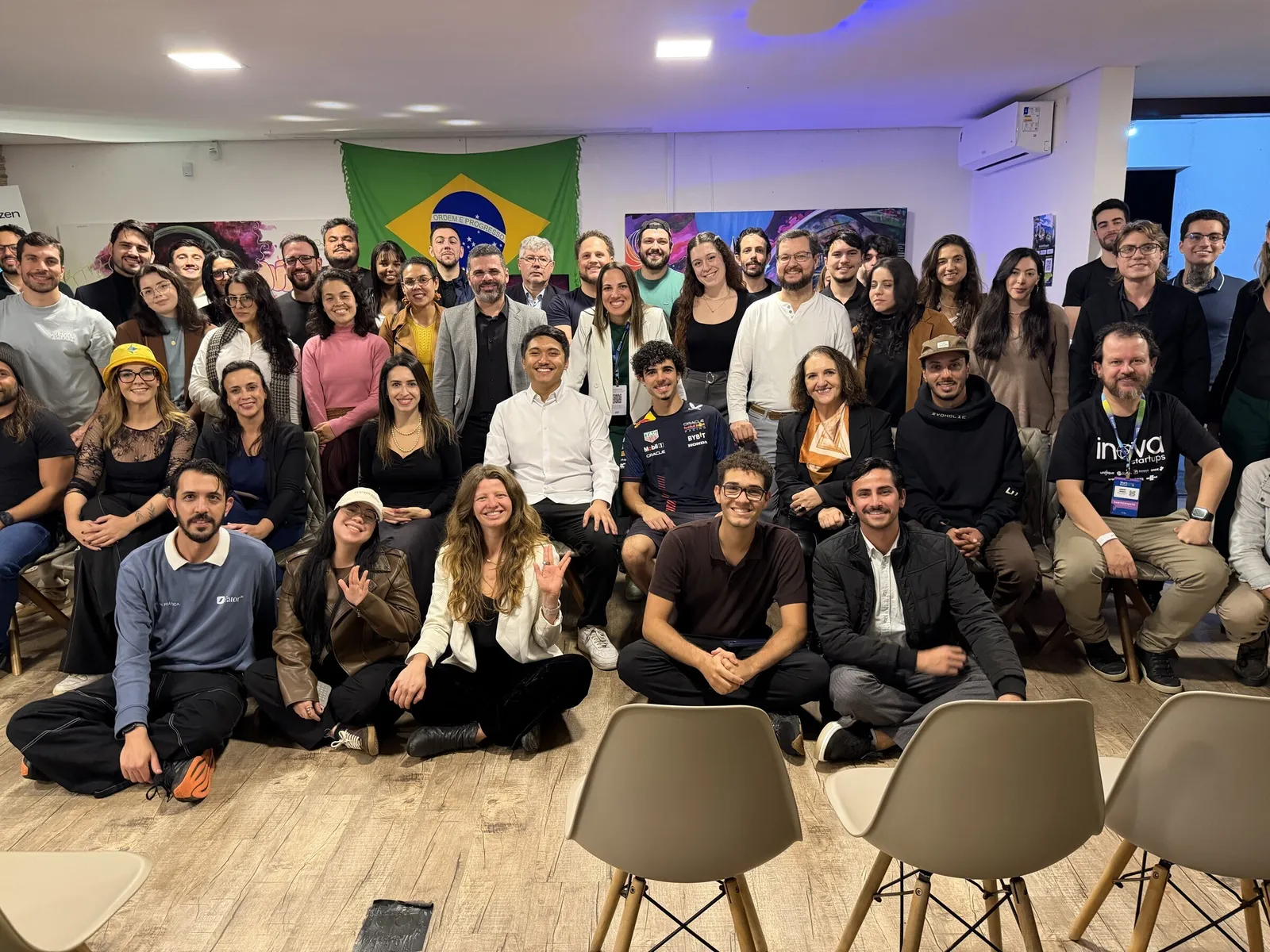 Group photo of about sixty people at Human × AI, smiling in front of a Brazilian flag.